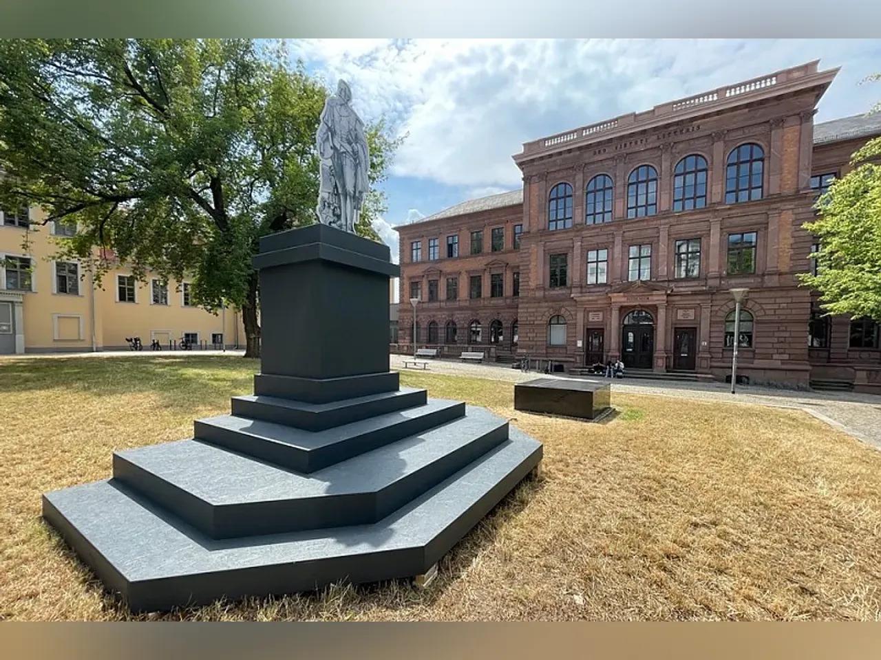 Auf dem Platz vor dem Rutheneum ist ein Sockel mit einer Figur aus Karton zu sehen, welche das zukünftige Denkmal symbolisieren soll.