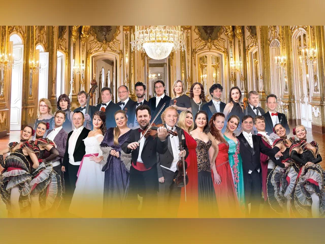 Ensemble der Richard Strauß Gala in festlicher Abendkleidung mit Instrumenten und Tänzer:innen in einem eleganten Spiegelsaal
