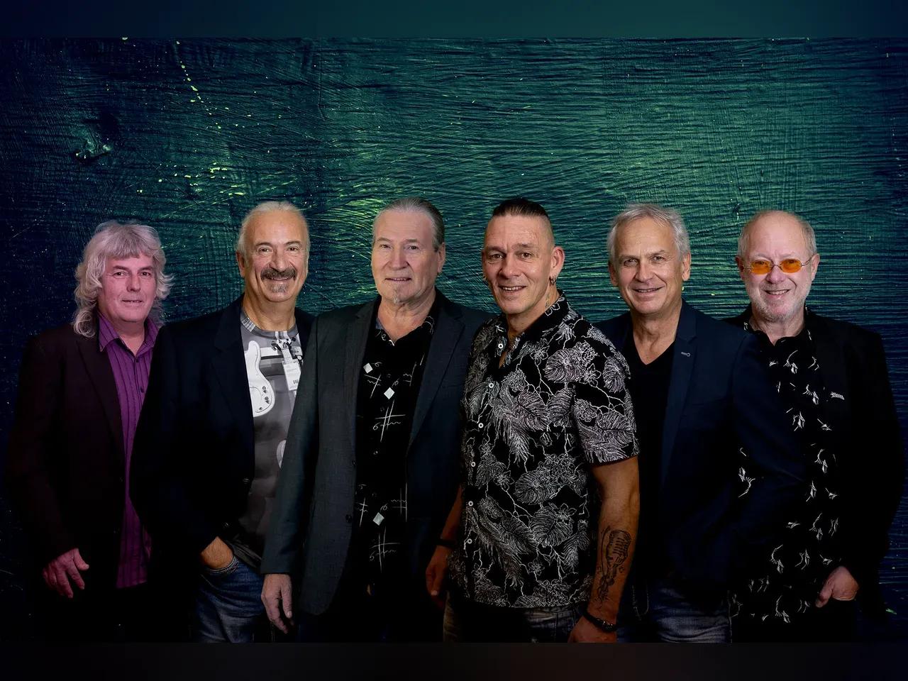 Sechs Herren der Partyband ROSA stehen vor einem grün besprengelten Hintergrund.