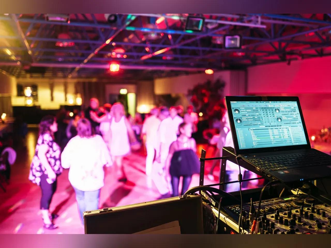 Tanzende Menschen im im bunt beleuchteten Saal des Stadtteilzentrums LISA, im Vordergrund ein DJ-Pult