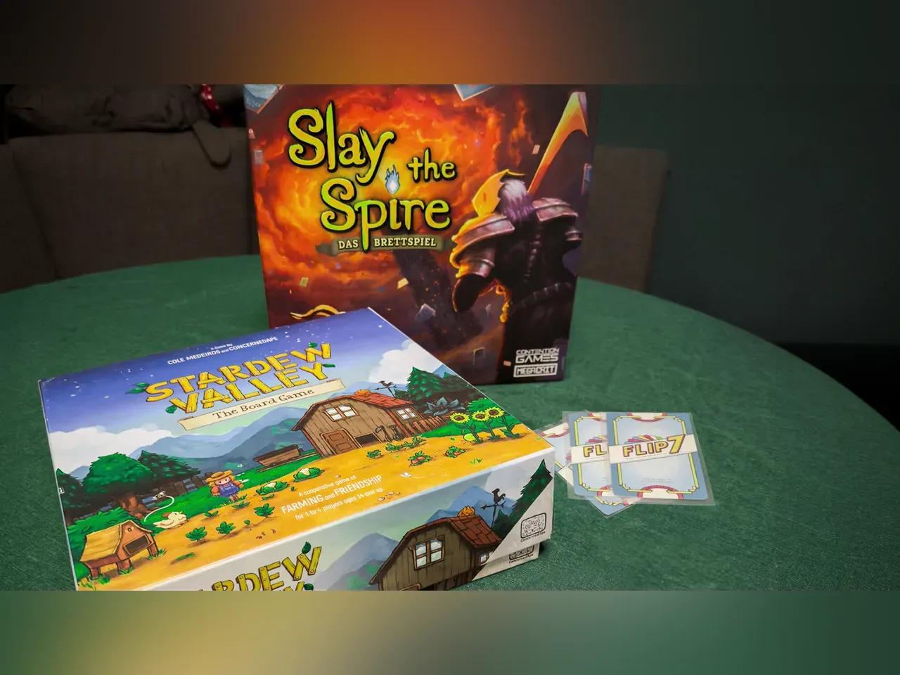 Auf einem Tisch sind die Spiele Slay the Spire, Flip 7 und Stardew Valley aufgestellt.