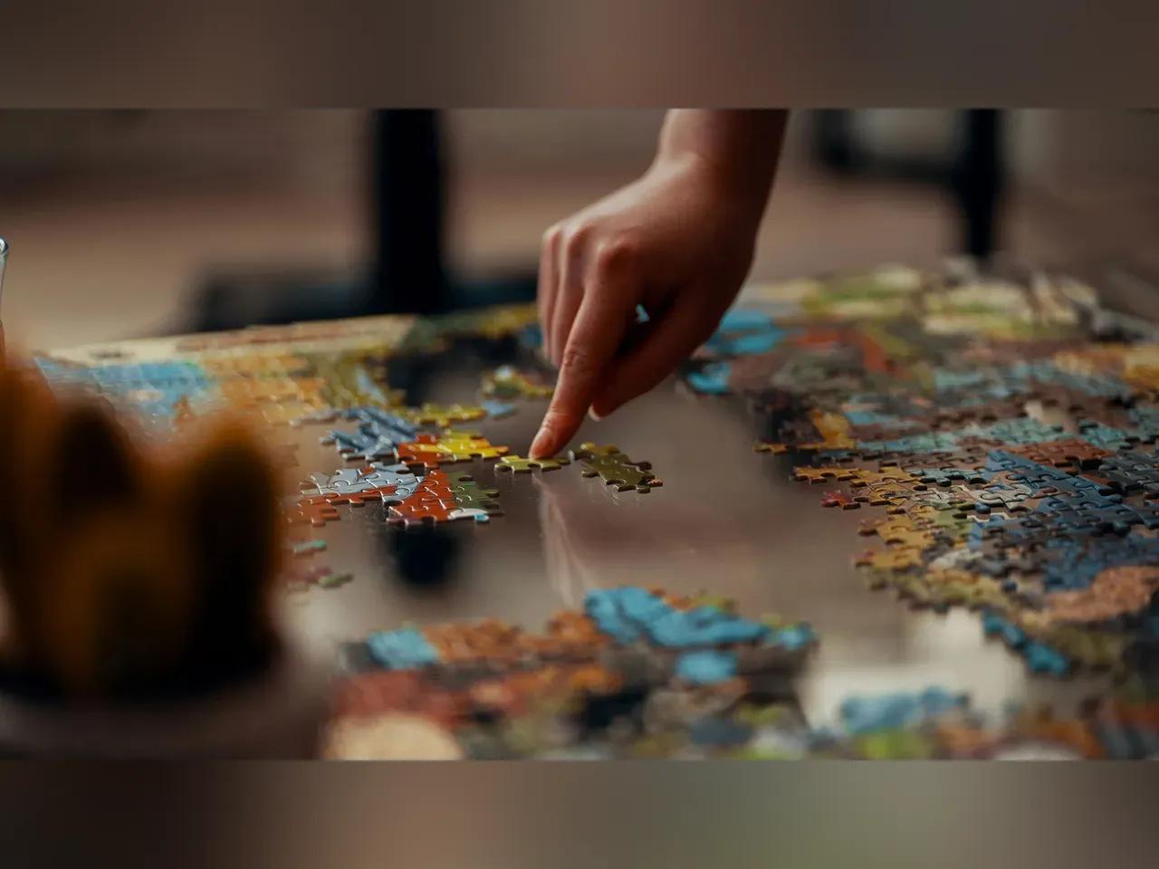 Ein buntes Puzzle das von zwei Händen zusammen gepuzzelt wird. 