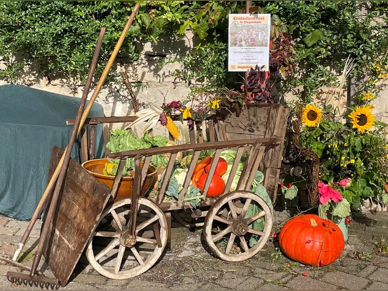 Herbstliche Dekoration mit einem alten Handwagen, Kürbissen und Sonnenblumen