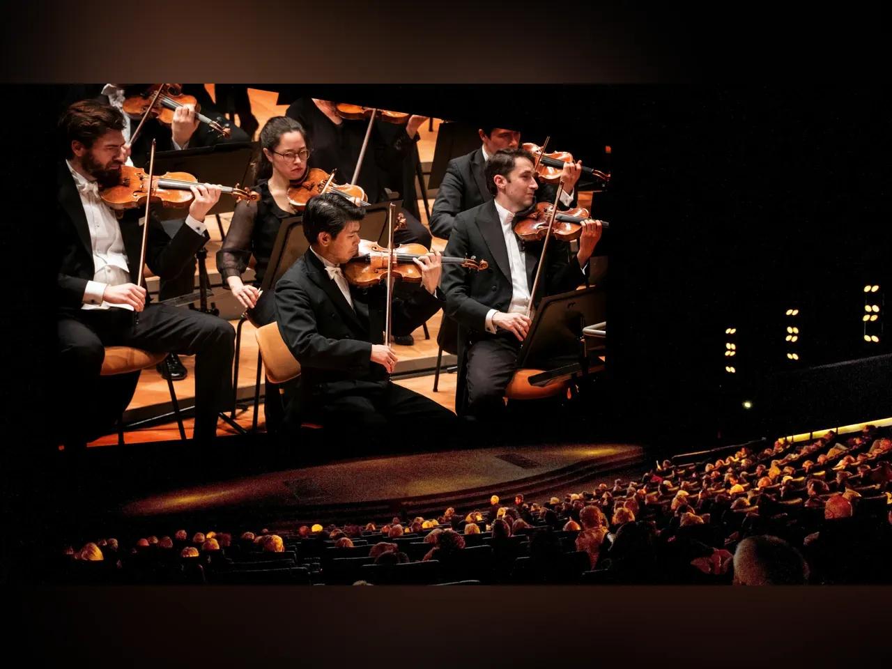 Kinoleinwand, auf der eine Übertragung eines Orchesterkonzerts läuft