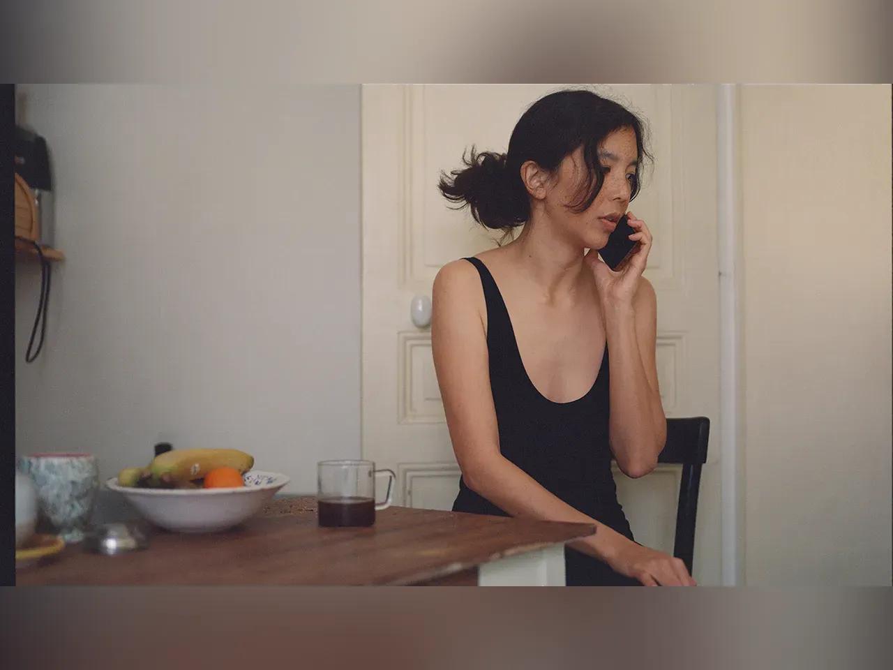 Musikerin Ana Roxanne sitzt an einem Tisch und telefoniert