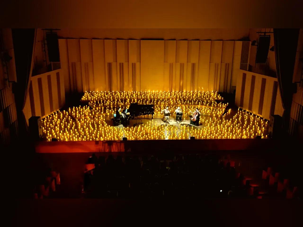 Musiker:innen auf einer Bühne mit vielen Kerzen